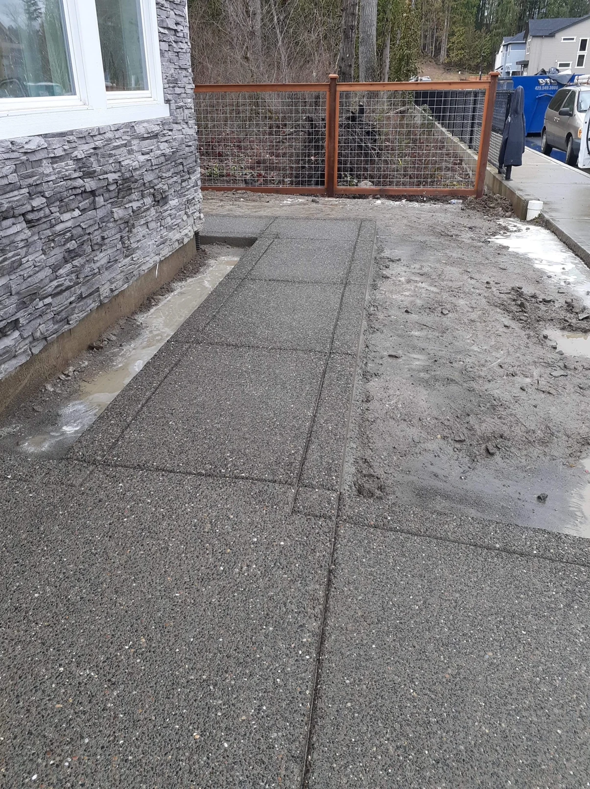 Exposed aggregate walkway turning around a stone-clad home