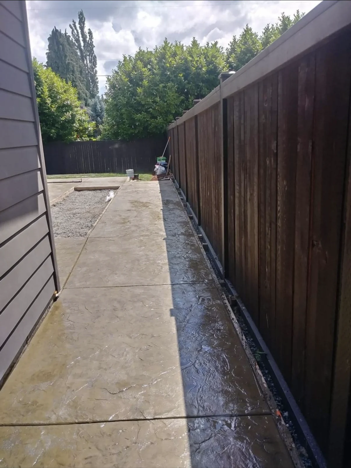 Stamped concrete side-yard walkway between a home and timber fence