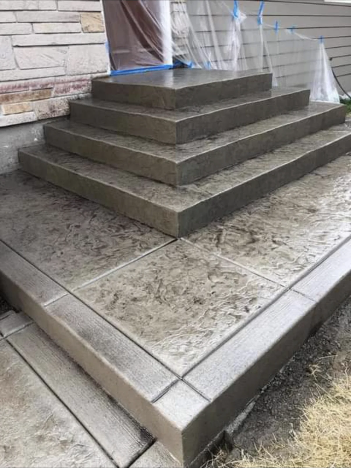 Tiered concrete entry steps above a stamped concrete landing